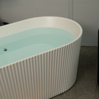 Modern freestanding bathtub with ribbed design and light blue interior.