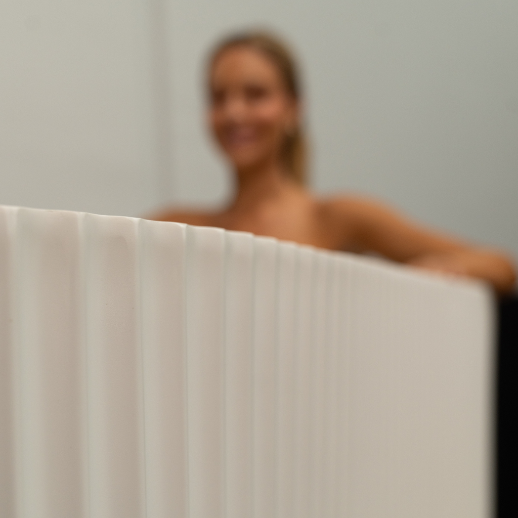 Blurred image of a person holding a white rectangular object against a neutral background