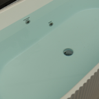 Close-up of a light blue bathtub with two drain holes.
