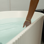 Person's hand reaching into a bathtub filled with water