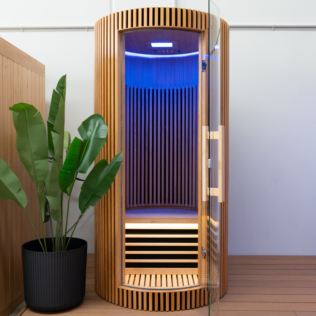 Wooden sauna with glass door, potted plant, and blue interior light.
