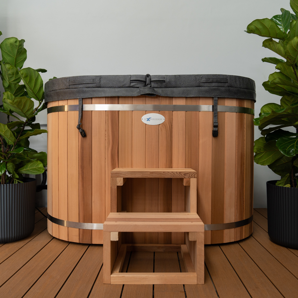 Wooden hot tub with step on a wooden deck, surrounded by potted plants.