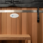 Wooden sauna with a metal strap and eXpress logo on a wooden panel