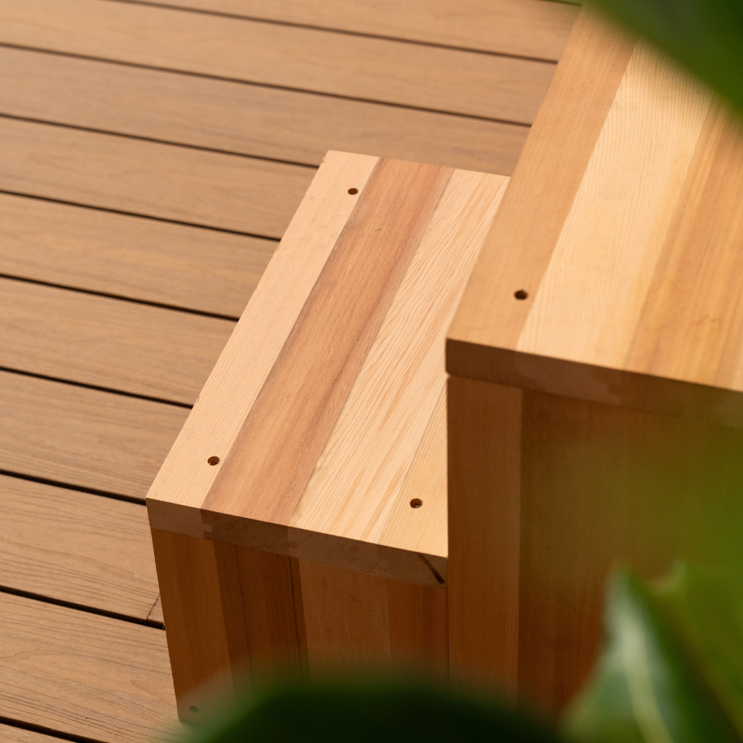 Wooden bench on a wooden deck with blurred greenery in the foreground