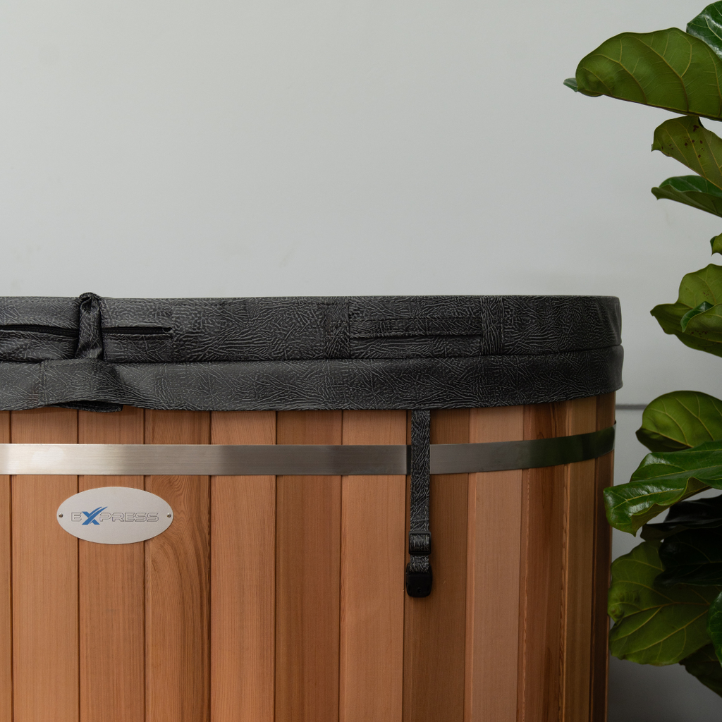 Wooden ice bath with black lid and metal handle, featuring a brand logo, against a neutral background.
