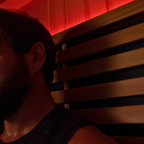 Person sitting in a wooden sauna with red lighting