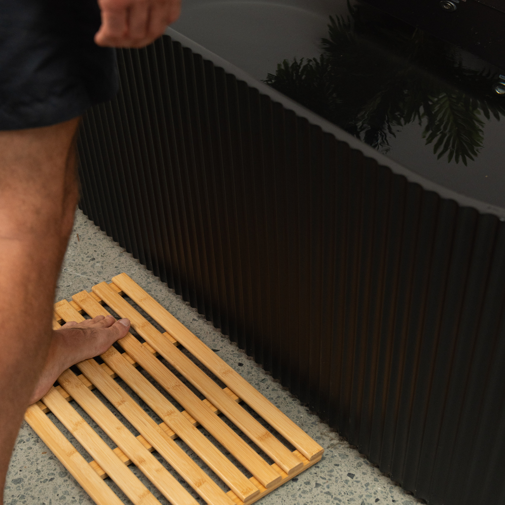 Person stepping onto a ice bath mat from a bathtub.