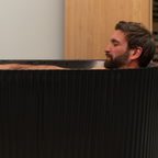 Man with a beard sitting in a black bathtub.