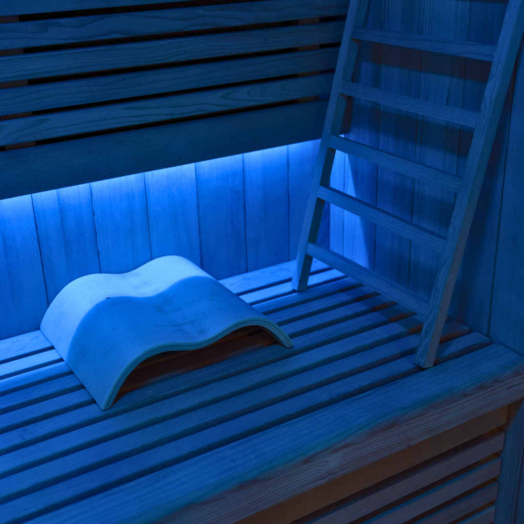 Infrared sauna with wooden bench and ladder, illuminated with blue light.