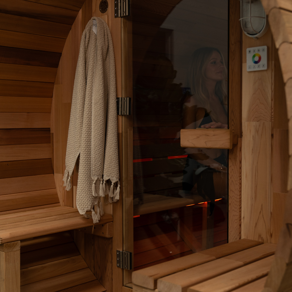 Person inside a wooden sauna with a towel hanging on the door.