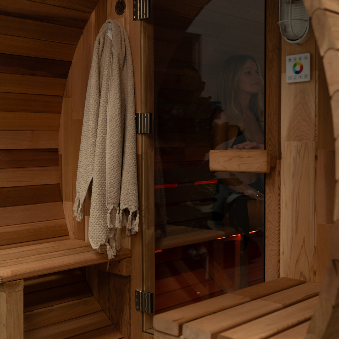 Person inside a wooden sauna with a towel hanging on the door.