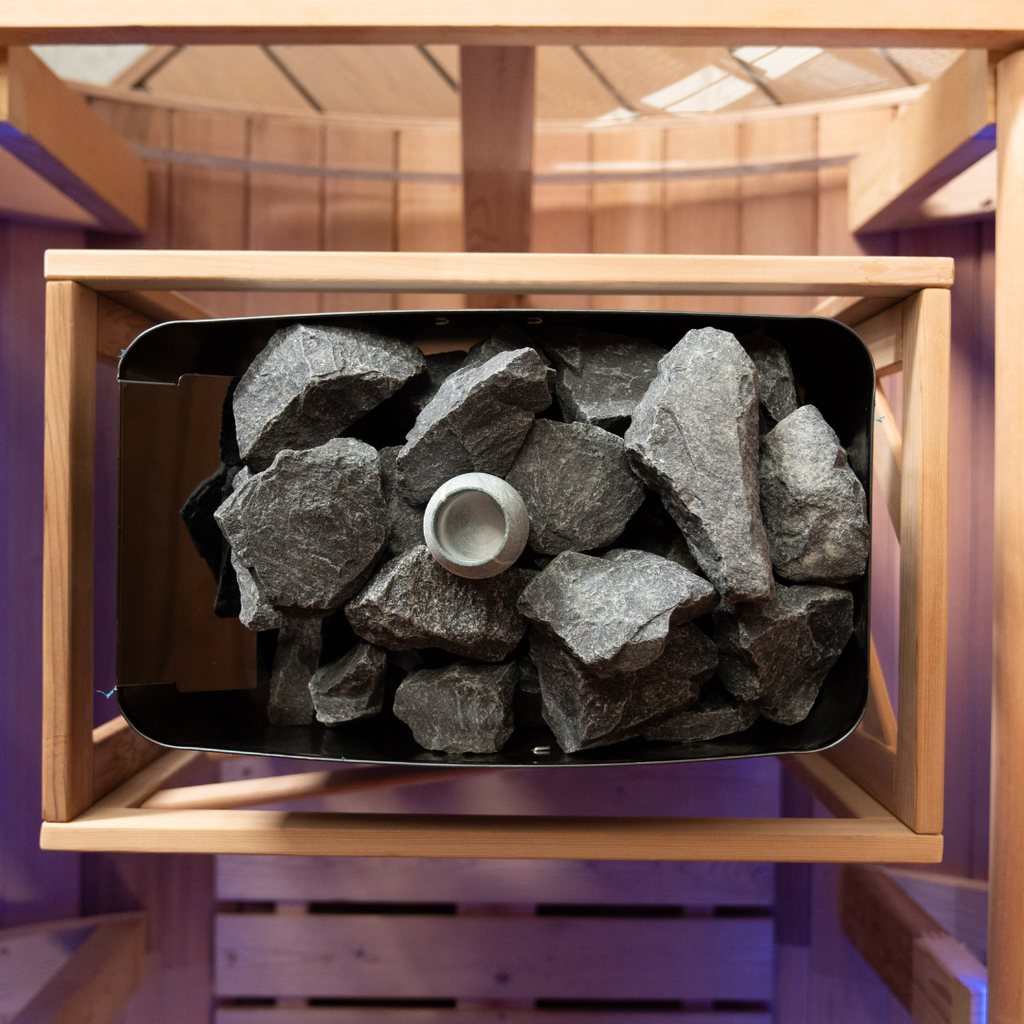 Wooden sauna with rocks and a candle inside, purple interior